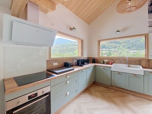 A modern kitchen with wooden cabinets, a built-in oven, and a large window offering a view of the outdoors. - Chalet des Filles -  7/9 peoples (Saint-Jean-d´Aulps)