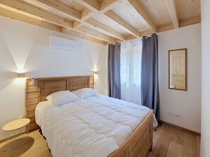 A bedroom with a wooden headboard, a bed with white bedding, a bedside table, and a window with curtains. - Chalet des Filles -  7/9 peoples (Saint-Jean-d´Aulps)