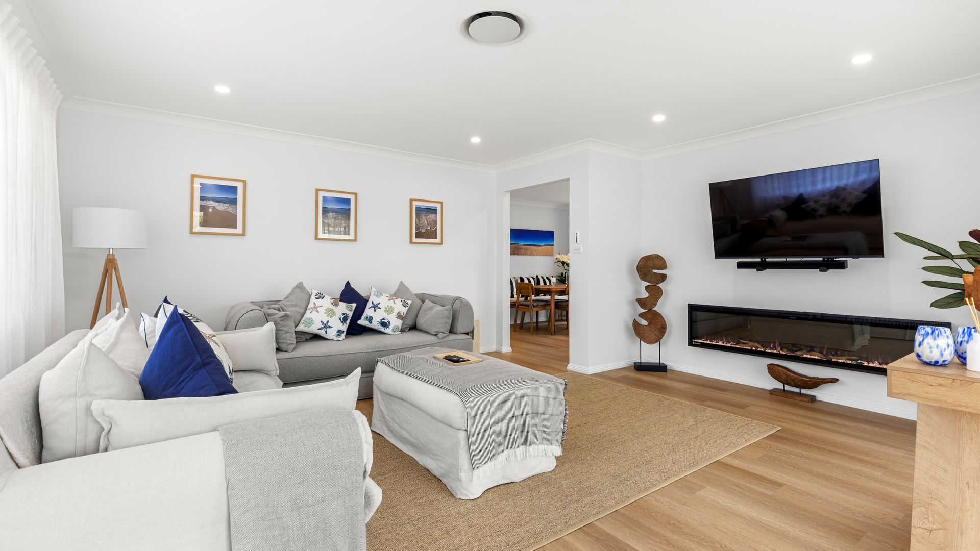 A modern living room with a sofa, a fireplace, a television, and framed pictures on the wall.