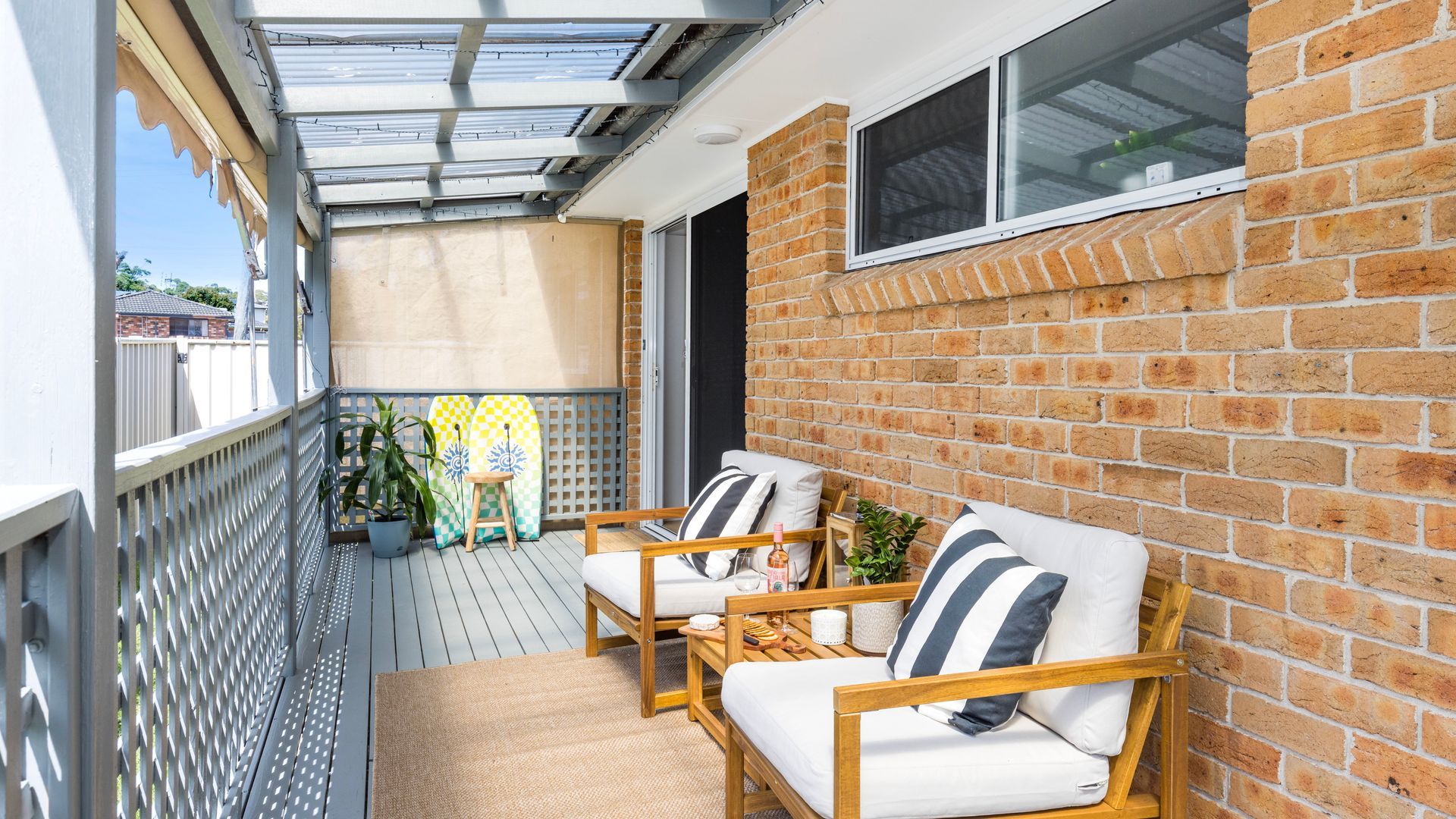 A covered outdoor seating area with a brick wall and a window.