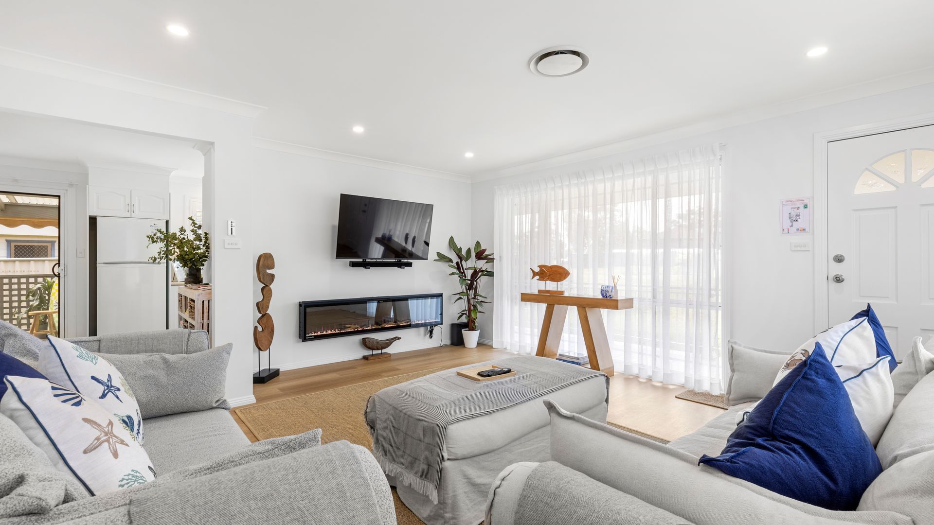 A modern living room with a fireplace, a flat-screen TV, and a dining area with a wooden table and chairs.