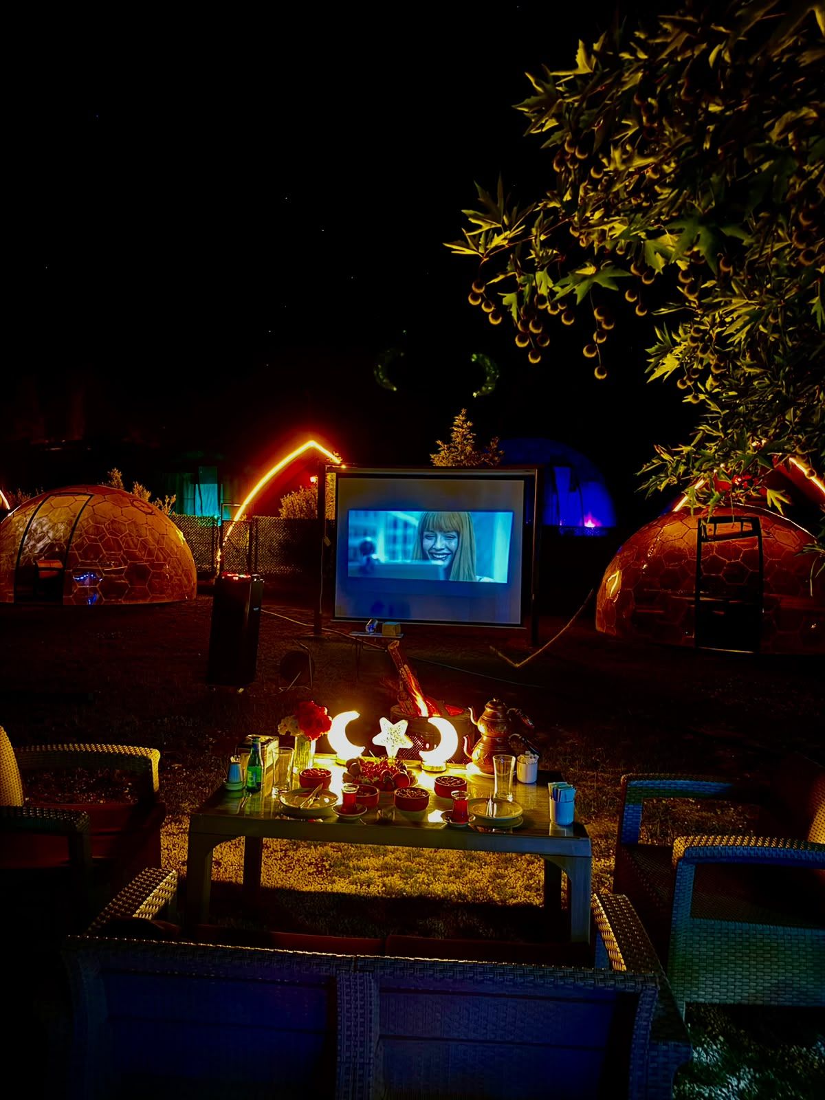 Un área de estar al aire libre acogedora, con una televisión, mesas y sillas.