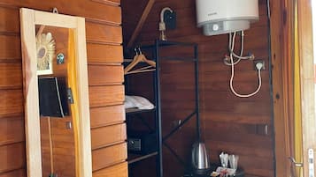 Quarto compacto com interior em madeira, aquecedor branco, pequena geladeira e espelho com moldura decorativa.