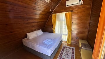 Quarto pequeno com painéis de madeira, uma cama de solteiro, um vaso sanitário e um ar condicionado.