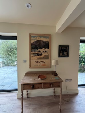 Ein Holztisch mit einer Schale, einem gerahmten Bild von Devon und einer Lampe.