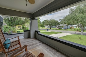 A covered porch with a wooden rocking chair and a view of a residential street. - 4BR Tampa Home, Easy Access to Dtwn (Tampa)