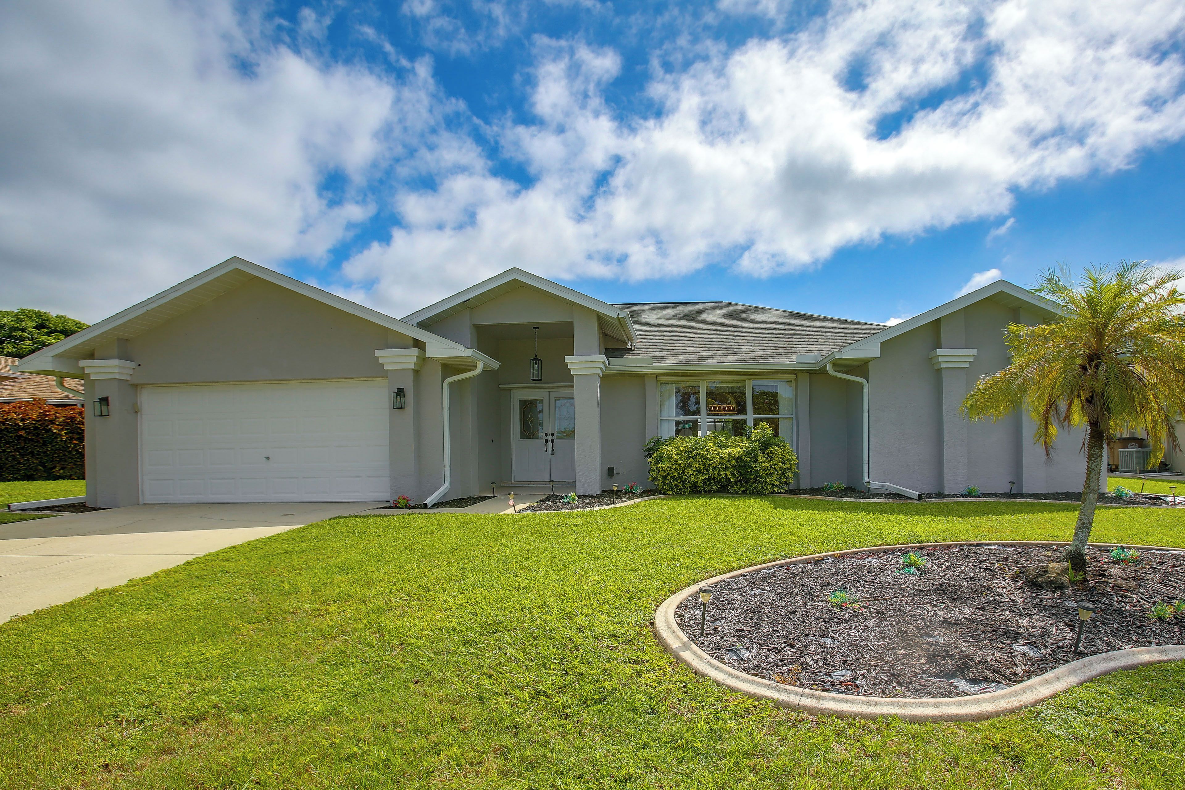A two-story house with a garage, a front porch, and a well-maintained lawn.