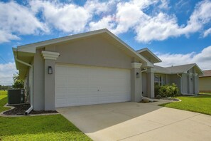 A residential house with a garage, a well-maintained lawn, and a clear sky. - Canal-front Home w/ Boat Lift & Pool in Cape Coral (Cape Coral)