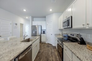 A modern kitchen with stainless steel appliances, white cabinetry, and granite countertops. - 'coastal Charm' Golf Getaway in Myrtle Beach (Myrtle Beach)
