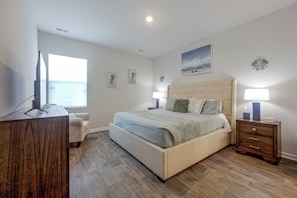 A bedroom with a large bed, bedside lamps, a desk, and a view of the sea. - 'coastal Charm' Golf Getaway in Myrtle Beach (Myrtle Beach)