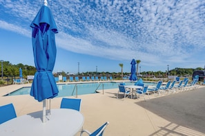 A poolside area with lounge chairs and umbrellas, a clear sky, and a distant view of a building. - 'coastal Charm' Golf Getaway in Myrtle Beach (Myrtle Beach)