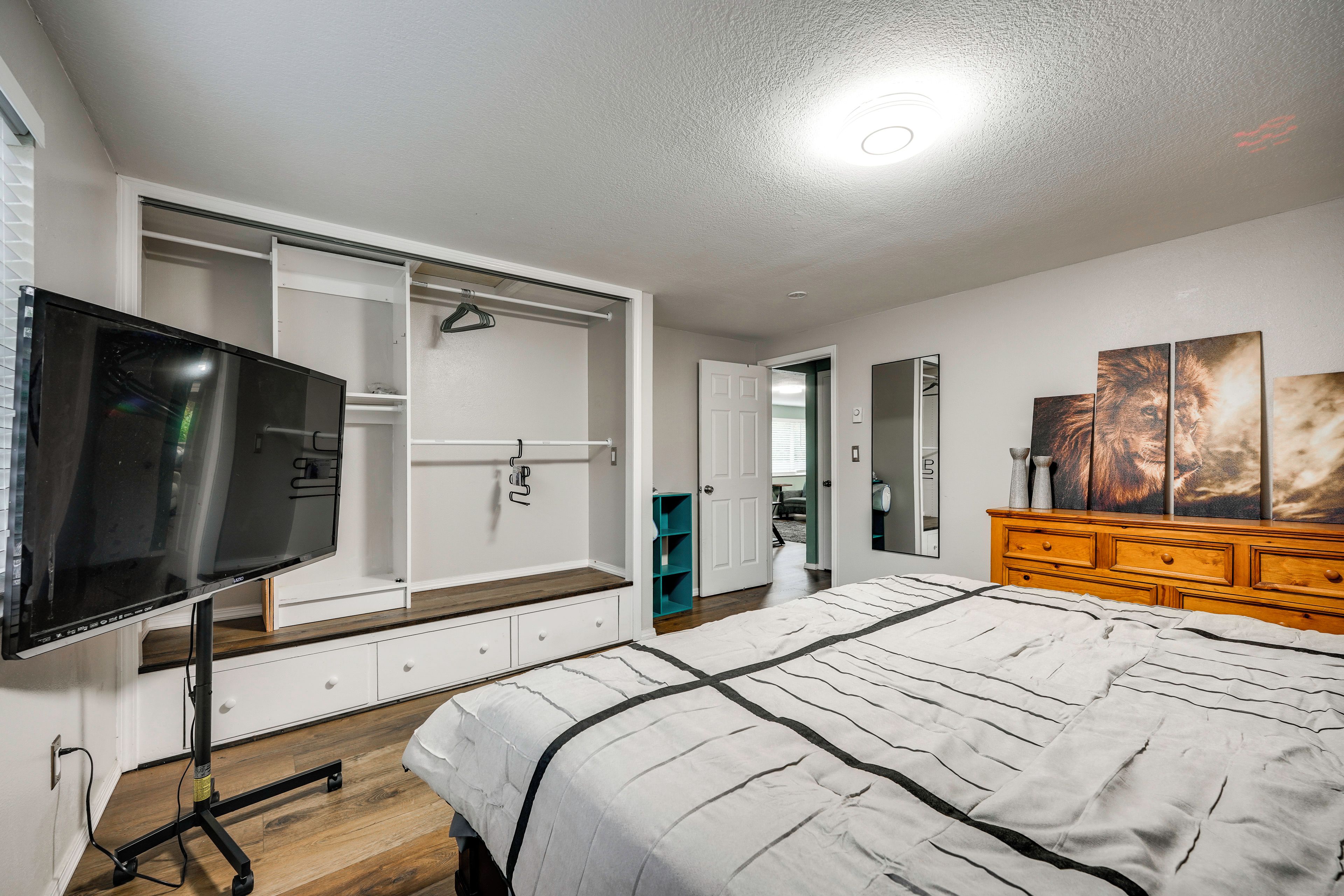 Een slaapkamer met een bed, een televisie, een kledingkast en een dressoir.
