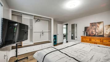Een slaapkamer met een bed, een televisie, een kledingkast en een dressoir.