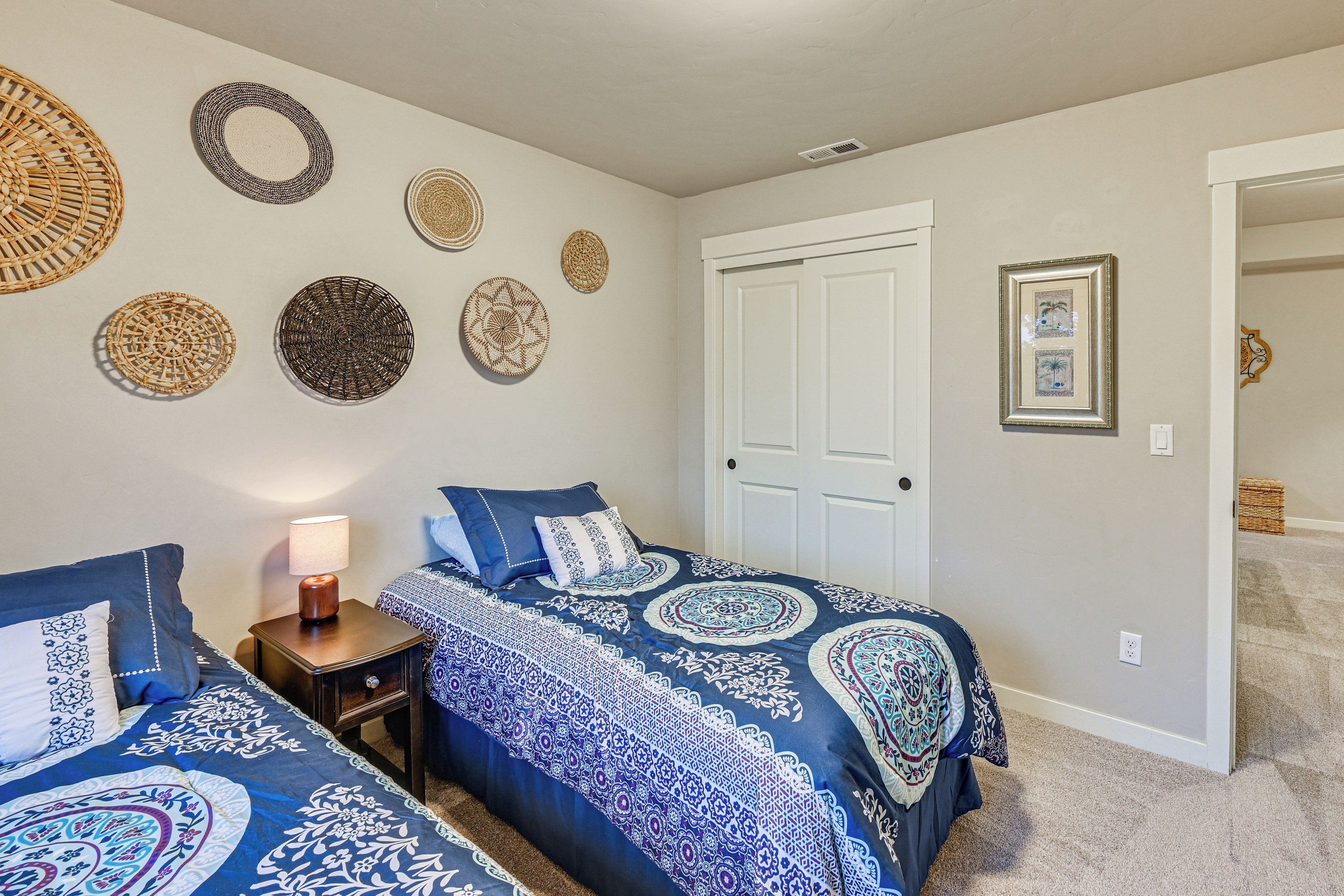 A bedroom with two beds, a nightstand, a lamp, and a door.