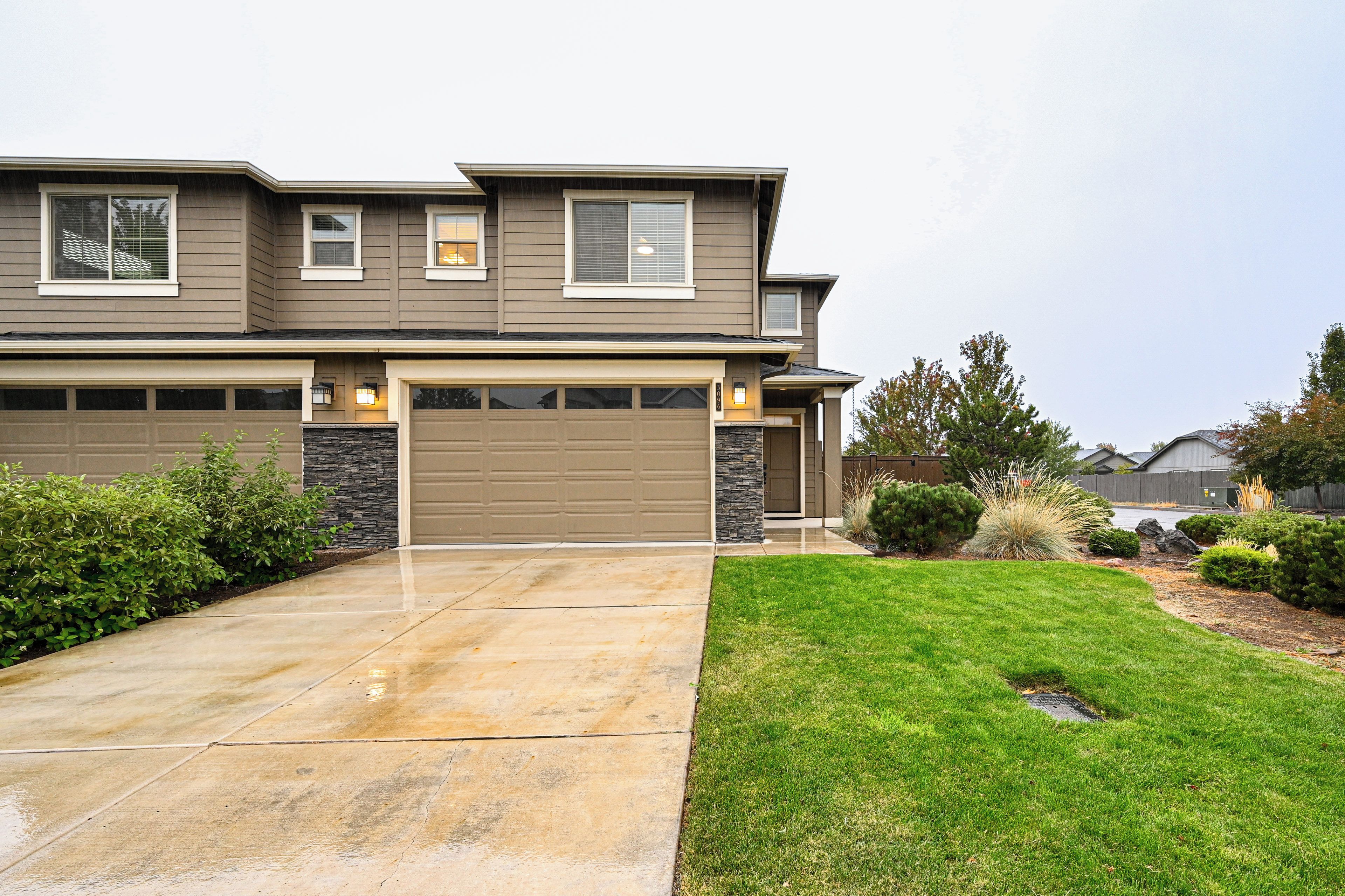 A two-story house with a garage, a stone accent wall, and a well-maintained lawn.