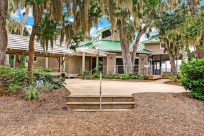 A building with a covered patio area, steps leading to the entrance, and a green roof. - Beautifully remodeled Ocean Front  Windsong Southend Resort (Fernandina Beach)