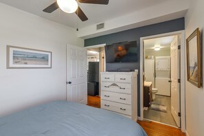 A bedroom with a bed, a dresser, a television, and a door leading to a bathroom. - Walk to Surfside Beach! Ocean-view Retreat w/ Yard (Freeport)