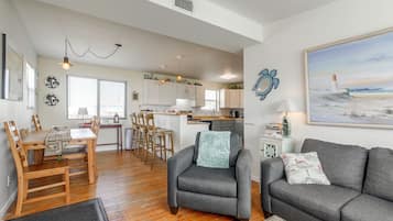 A spacious living area with a dining table, two sofas, and a kitchen in the background.