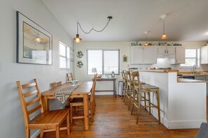 A spacious kitchen with wooden furniture, a dining area, and a view of the cityscape through the windows. - Walk to Surfside Beach! Ocean-view Retreat w/ Yard (Freeport)