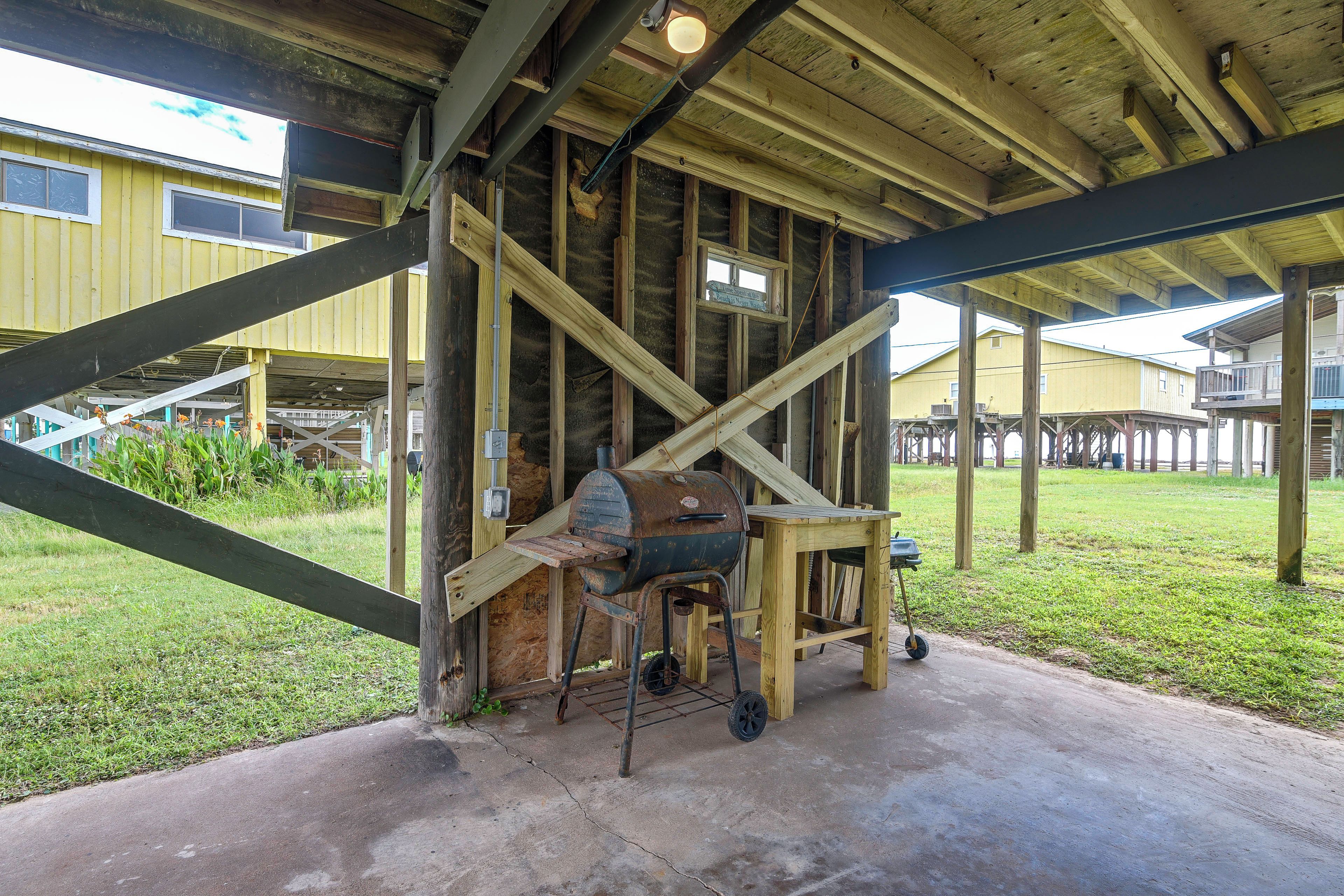 A covered outdoor area with a wooden structure, a grill, and a wheelbarrow.
