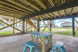 Un espacio al aire libre cubierto con una mesa de madera y dos taburetes, una escalera y vistas de edificios al fondo.