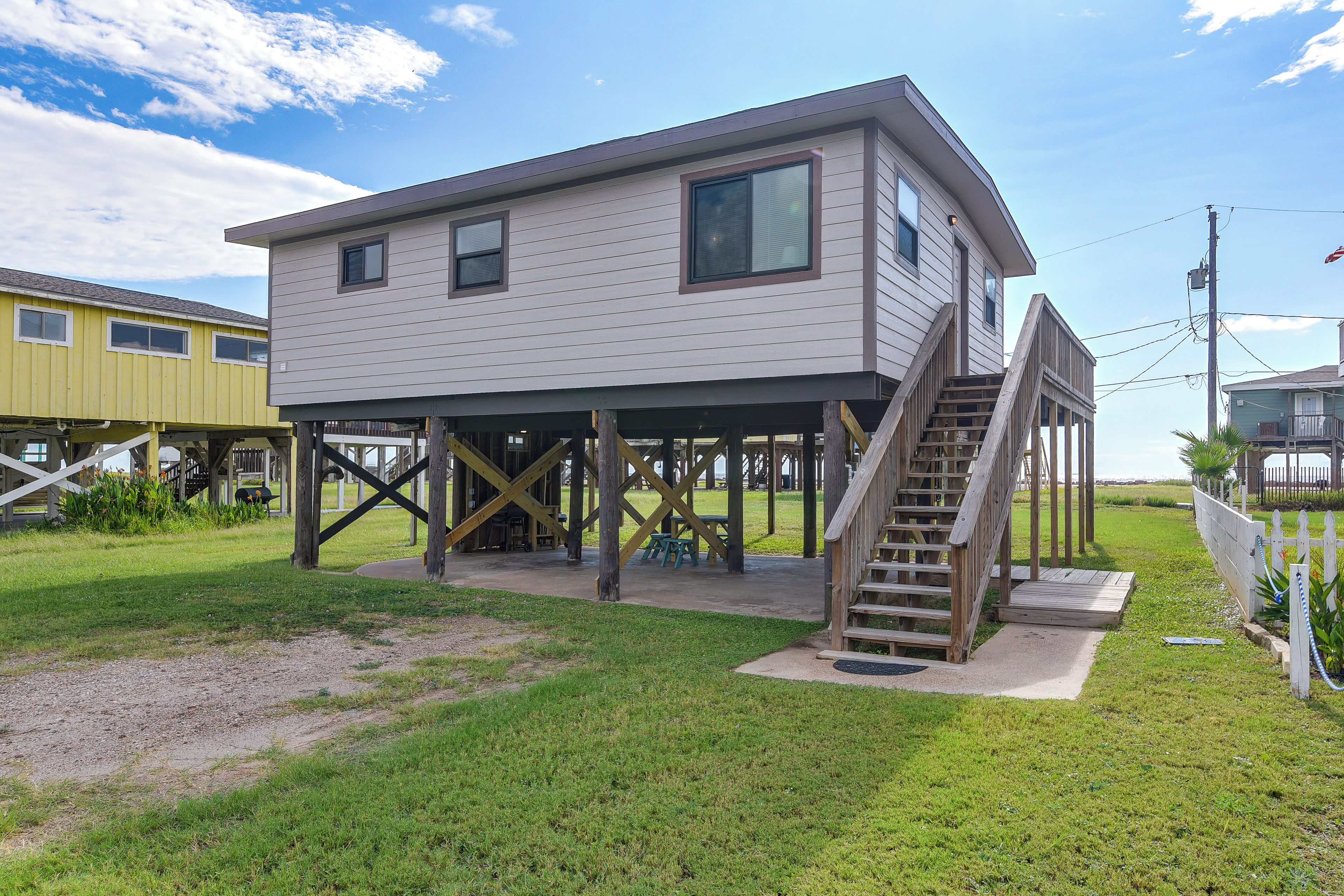 A two-story house with a wooden deck and a staircase leading to an upper level.