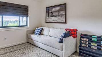 A living room with a sofa, a painting, a window, and a storage unit with labels.