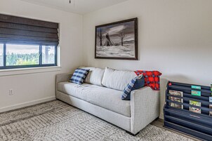 A living room with a sofa, a painting, a window, and a storage unit with labels.