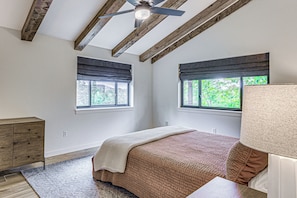 A bedroom with a wooden ceiling, two windows with blinds, a bed with a patterned bedspread, a bedside table, and a dresser. - Home Near Ski Cloudcroft & Lincoln Natl Forest! (Cloudcroft)