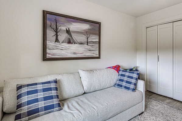 A living room with a sofa, pillows, a painting, and a wardrobe. - Home Near Ski Cloudcroft & Lincoln Natl Forest! (Cloudcroft)