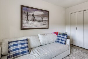 A living room with a sofa, pillows, a painting, and a wardrobe.