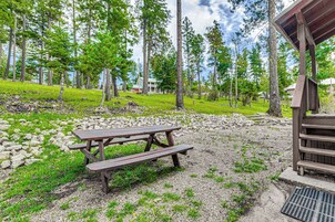 A picnic table in a forested area with a wooden structure nearby.