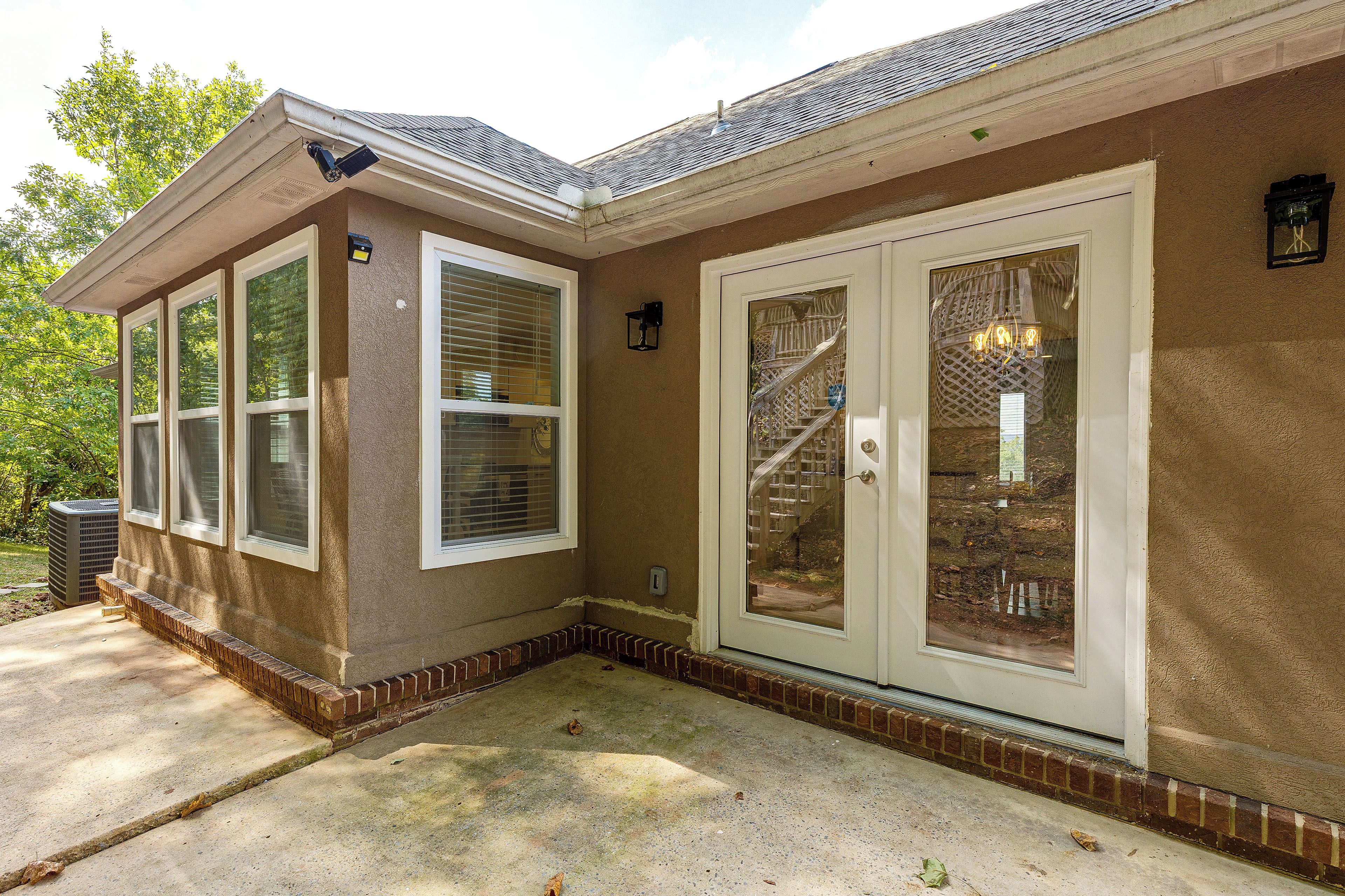 A residential building with a covered porch, a garage, and a large sliding glass door.