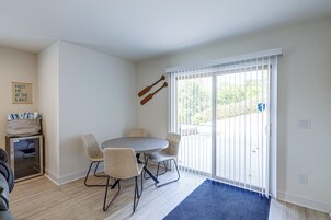 Una habitación con una mesa redonda y cuatro sillas, un archivador pequeño y una puerta corredera de vidrio que da a un espacio exterior.