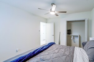 Un dormitorio con cama, ventilador de techo, una puerta y armario.