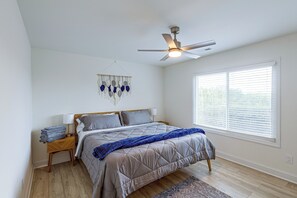 A bedroom with a bed, a ceiling fan, a wall hanging, and a window with blinds. - Deck & Game Room! Modern Lake Guntersville Retreat (Guntersville)