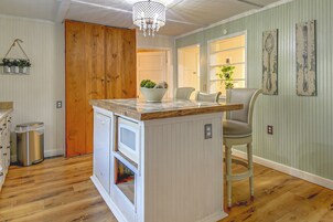 Una cocina con una isla de madera, una planta colgante y una araña.