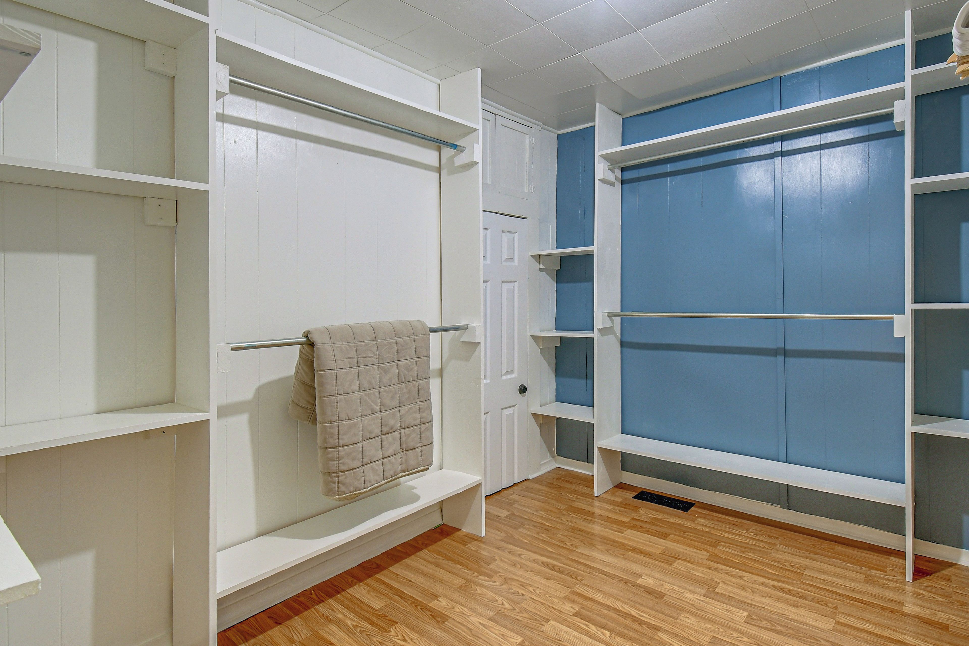 A room with white shelving units and a blue door.
