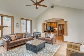 A spacious living room with leather sofas, a coffee table, and a patterned rug. - New! Private Lakefront Retreat on Lindstrom Lake (Lindstrom)