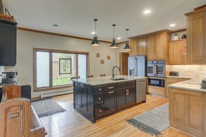 A modern kitchen with a large island, wooden cabinets, and a built-in oven. - New! Private Lakefront Retreat on Lindstrom Lake (Lindstrom)
