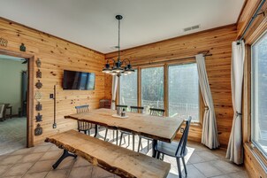 A wooden interior with a dining table, benches, and a TV mounted on the wall.