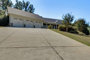 A residential garage with a concrete driveway leading to a house with a sloped roof.