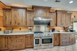 Una cocina con armarios de madera, una campana extractora de acero inoxidable, una estufa a gas y un horno empotrado.
