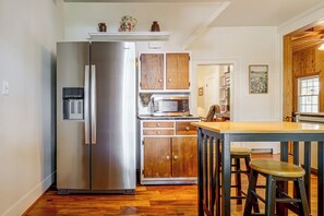 A compact kitchen with a stainless steel refrigerator, a microwave, wooden cabinets, and a wooden bar stool. - Sauna & Fire Pit, Quiet 2-unit Combo in Broadway (Broadway)