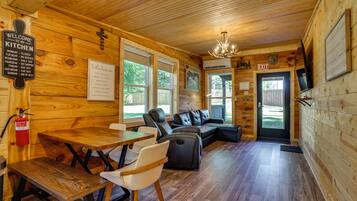 A wooden interior with a dining area, seating, and a kitchen sign.