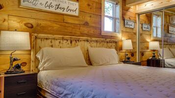 A wooden room with a bed, two bedside tables, a mirror, and wall decorations.