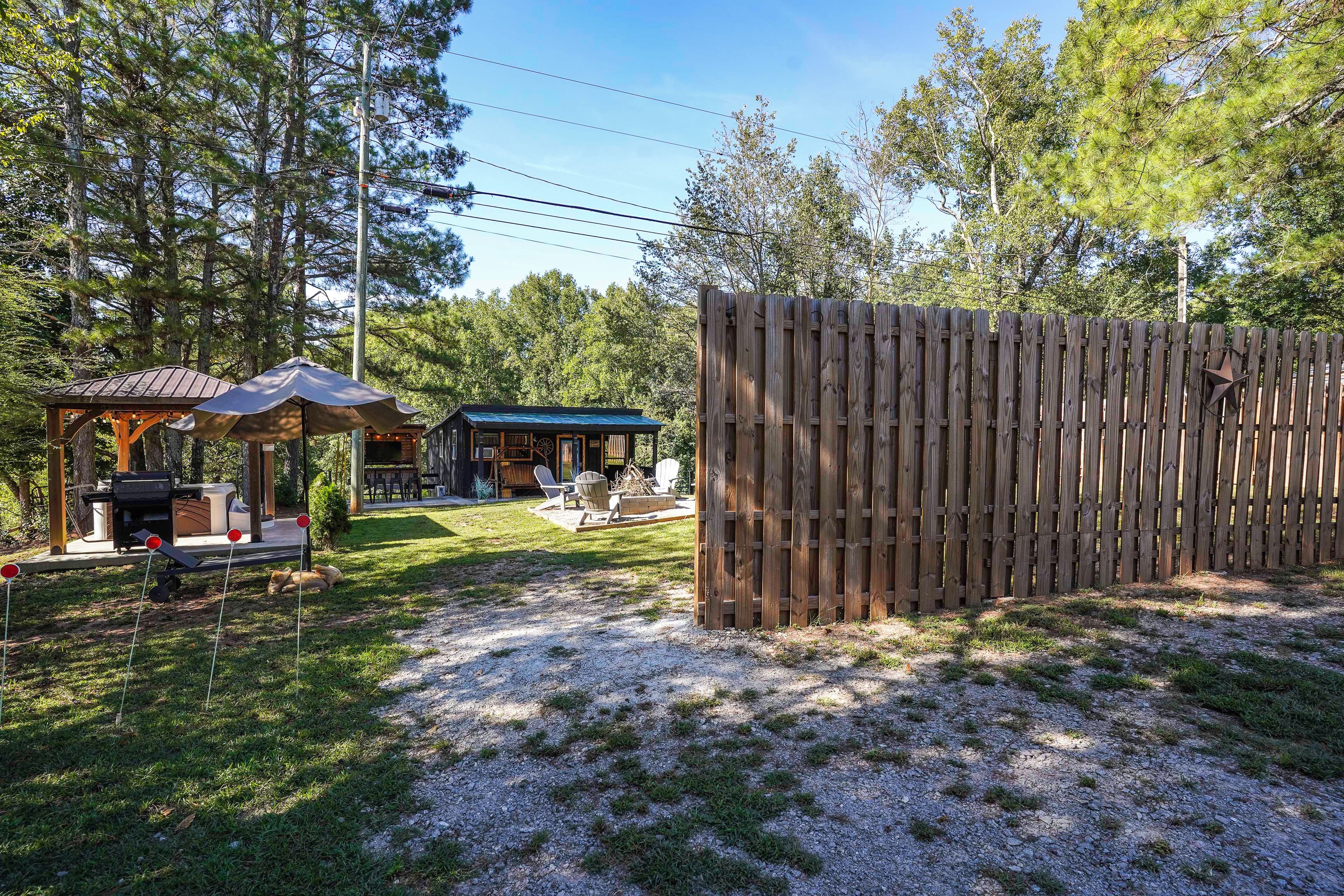 Une clôture en bois, un espace extérieur aménagé avec un toit, et un bâtiment avec un toit bleu.
