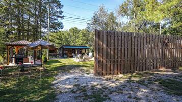 Une clôture en bois, un espace extérieur aménagé avec un toit, et un bâtiment avec un toit bleu.