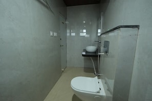 Un baño pequeño y cerrado con inodoro, lavabo y zona de ducha.