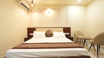 Una habitación de hotel con una cama grande, mesitas de noche, una silla y un escritorio.
